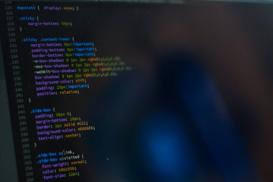 A close-up view of a computer screen displaying lines of code in various colors, including green, purple, orange, and blue, on a dark background. The code appears to be related to programming or web d