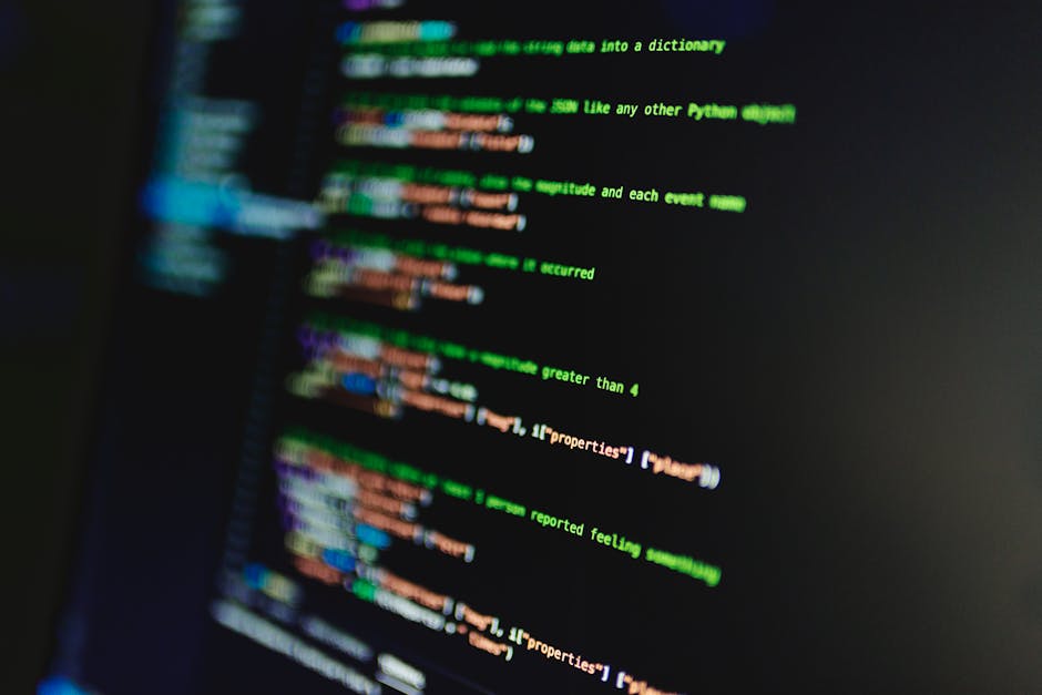 The image depicts a close-up view of a computer screen displaying colorful lines of programming code. The code features syntax highlighted in various colors, including green, orange, blue, and purple,